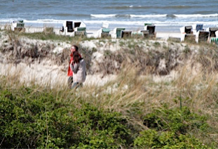 Eine Inseldünen-Landschaft an der Nordsee mit Strandköben und Gästen im Hintergrund